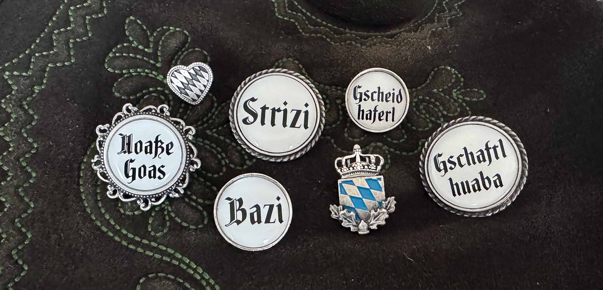 Verschiedene Pins mit bayerischen Schimpfwörtern