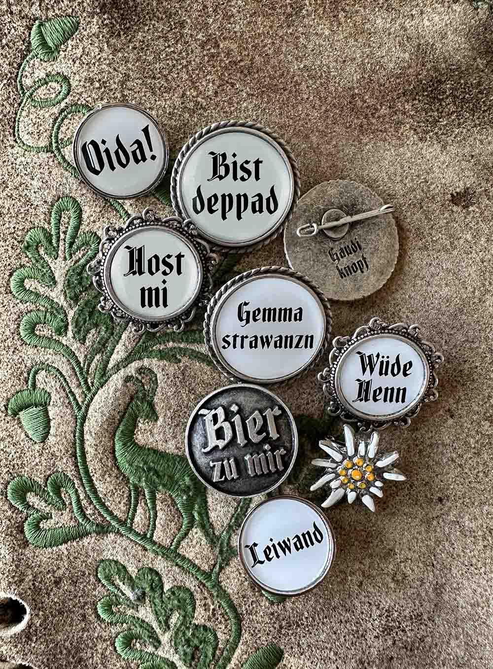 Anstecker mit verschiedenen österreichischen Ausdrücken auf Lederhose.
